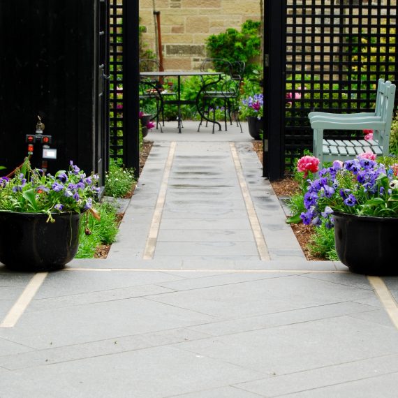Side garden view through black square trellis, black basalt path with Clashach inlay, designed by Carolyn Grohmann