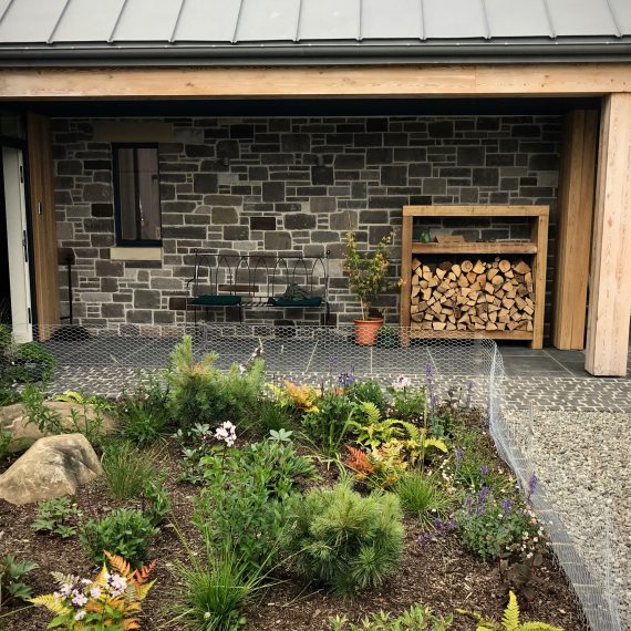 Front door area: bench, logstore, planting. Designed by Carolyn Grohmann