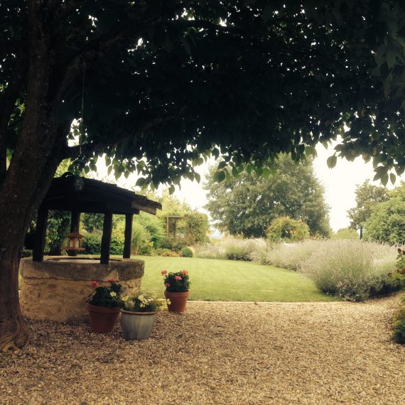 Old stone well and view across the garden. Garden designed by Carolyn Grohmann