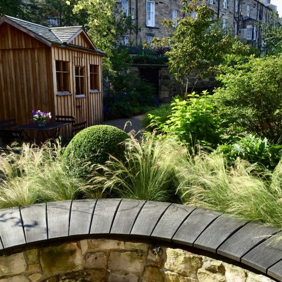 Scottish larch garden shed with stone bench and scorched oak seat