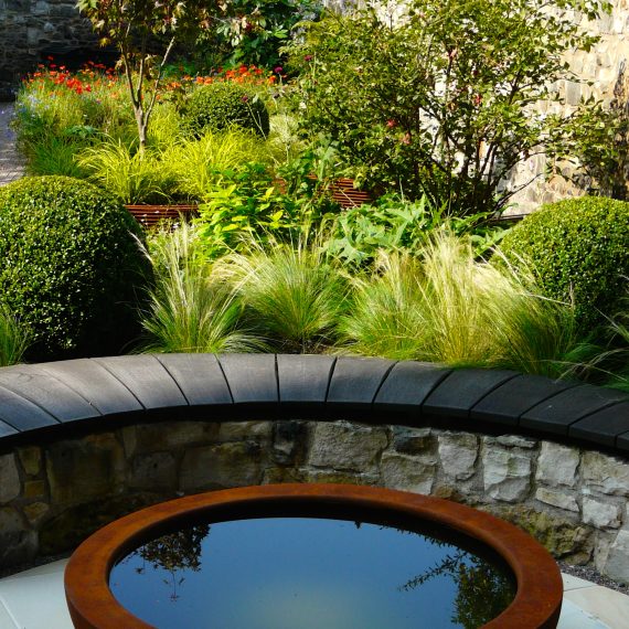 Curved stone wall, oak bench top and Urbis lily bowl