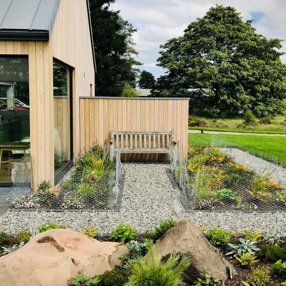 Timber wall creating shelter from the wind with seating on both sides. Designed by Carolyn Grohmann