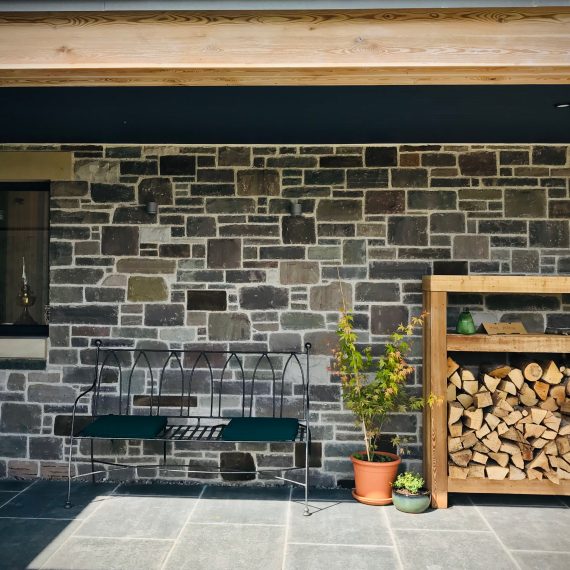 Covered front door area with bench, log store. Designed by Carolyn Grohmann