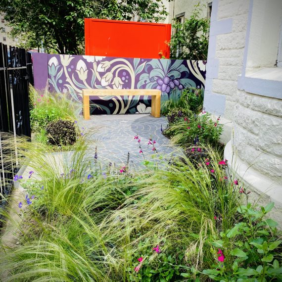 City garden, street art by Phil Blake, frothy planting and larch bench. Garden designed by Carolyn Grohmann